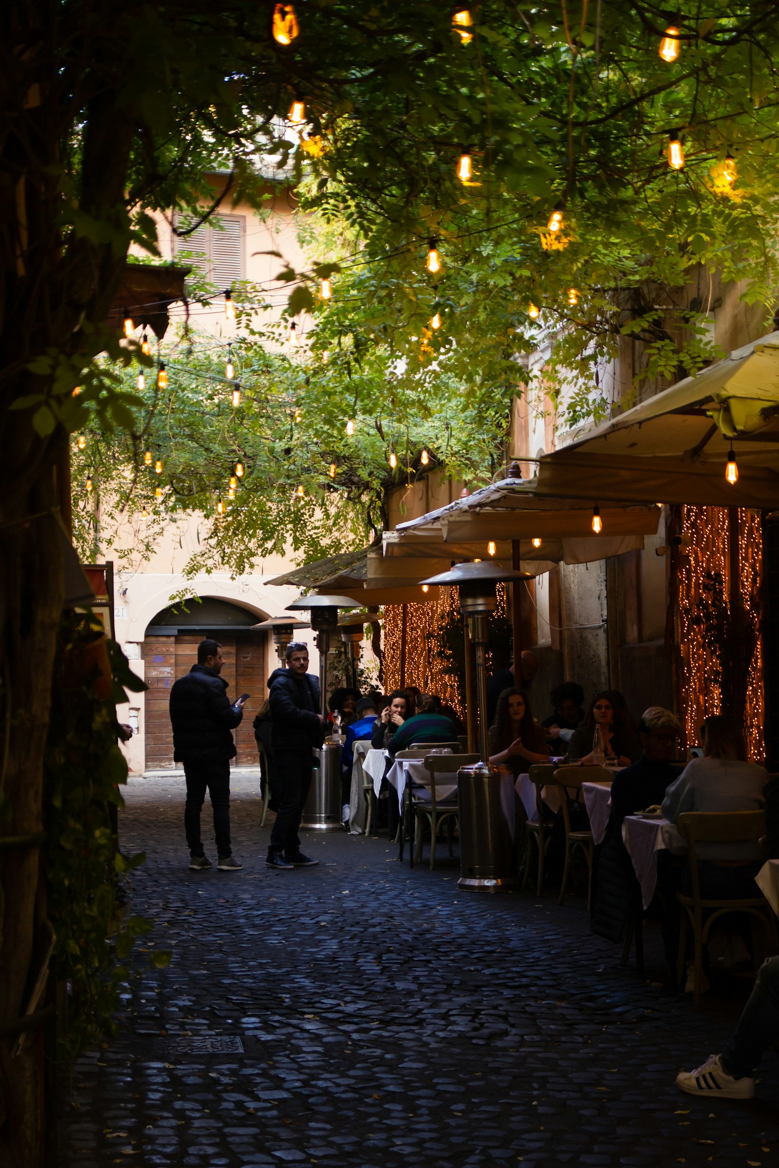 Callejuela napolitana con mesas al aire libre y luces cálidas